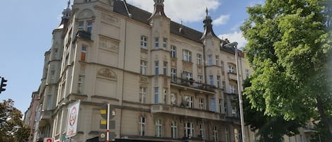 Un immeuble à plusieurs étages, doté de détails architecturaux raffinés, notamment une horloge et des éléments décoratifs sur la façade.