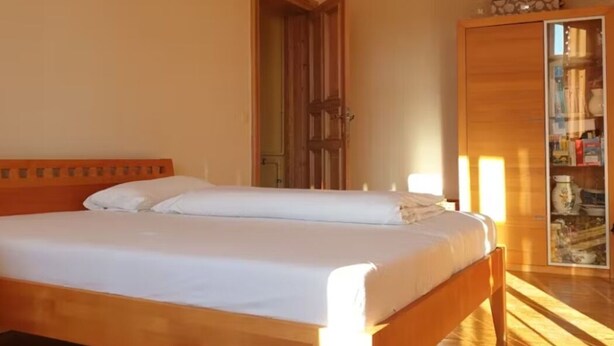 A bedroom with a wooden bed, a wardrobe, and a door leading to another room. - Zimmer in Centrum von Berlin (Berlin)