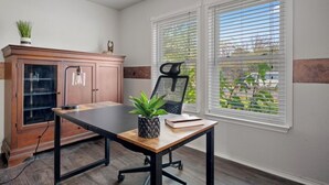 A room with a desk, a chair, a cabinet, and a window with blinds.