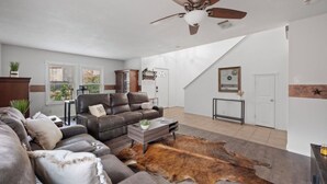 A spacious living room with a leather sofa, a coffee table, and a ceiling fan.