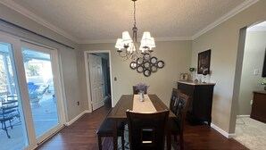 A dining area with a chandelier, a dining table, chairs, and a view through a glass door.