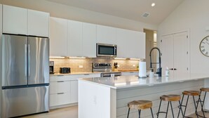 A modern kitchen with stainless steel appliances, a microwave, and a large island with bar stools.