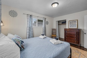 A bedroom with a bed, a dresser, a wardrobe, and a ceiling light.