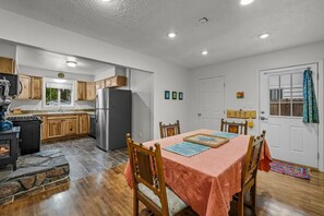 A modern kitchen with a large refrigerator, wooden cabinets, and a stone fireplace. - Midtown Home, Office+Fiber, Fenced Yard, Pets OK (Bend)