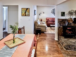 A dining area with a wooden table and chairs, a vase with greenery, and a rug. - Midtown Home, Office+Fiber, Fenced Yard, Pets OK (Bend)