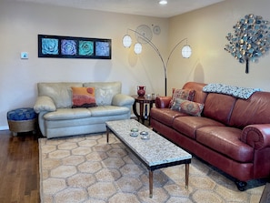 A living room with two sofas, a coffee table, and decorative wall art.