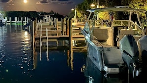 A marina at night with boats docked, wooden walkways, and a calm water surface reflecting the lights.