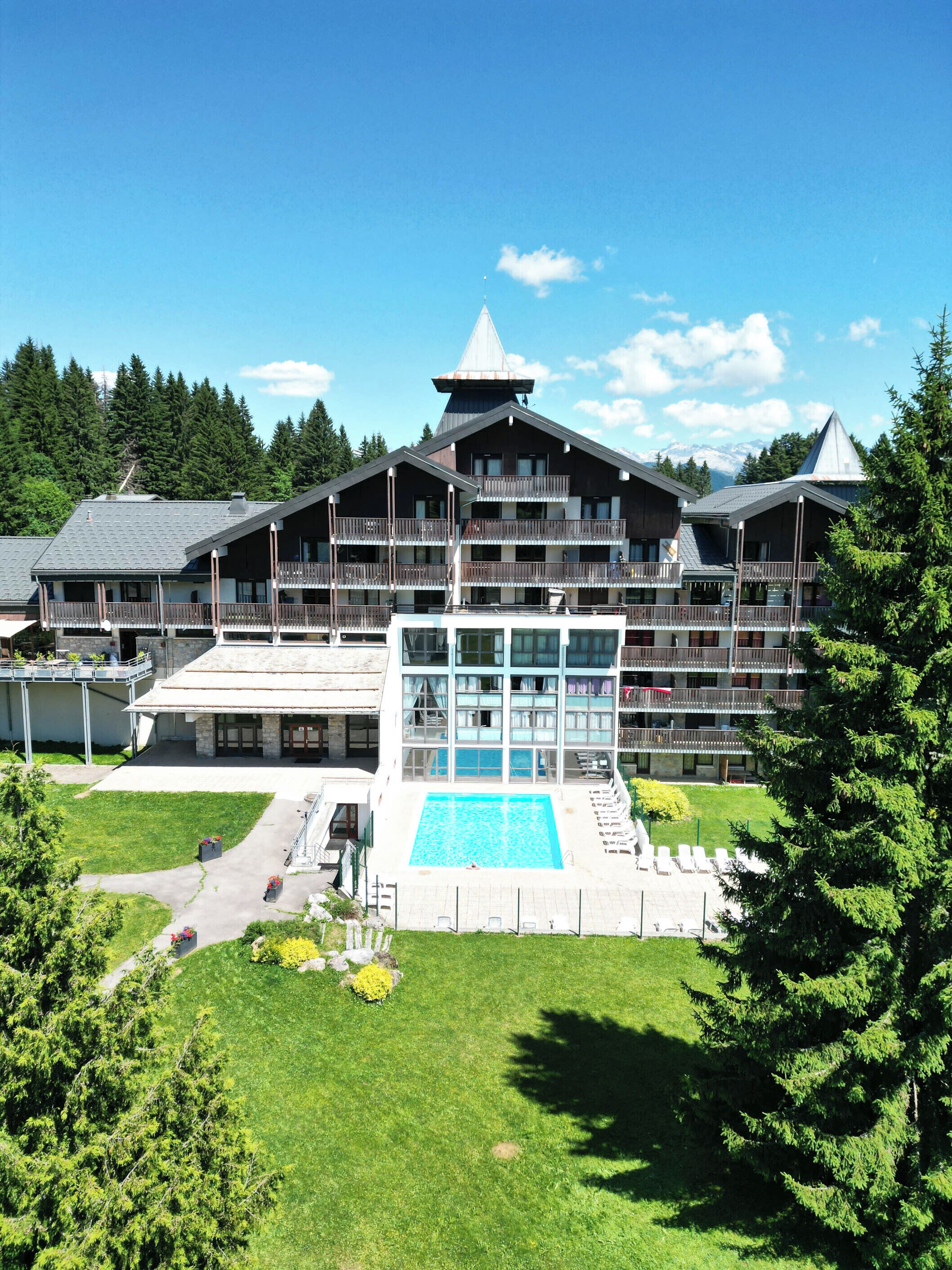 Un hôtel doté d’une grande piscine, de nombreux balcons et offrant une vue sur un paysage montagneux.
