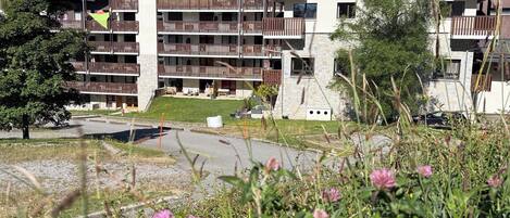 Et hotel med flere etager, altaner, en stenfacade og et bjergrigt landskab i baggrunden.