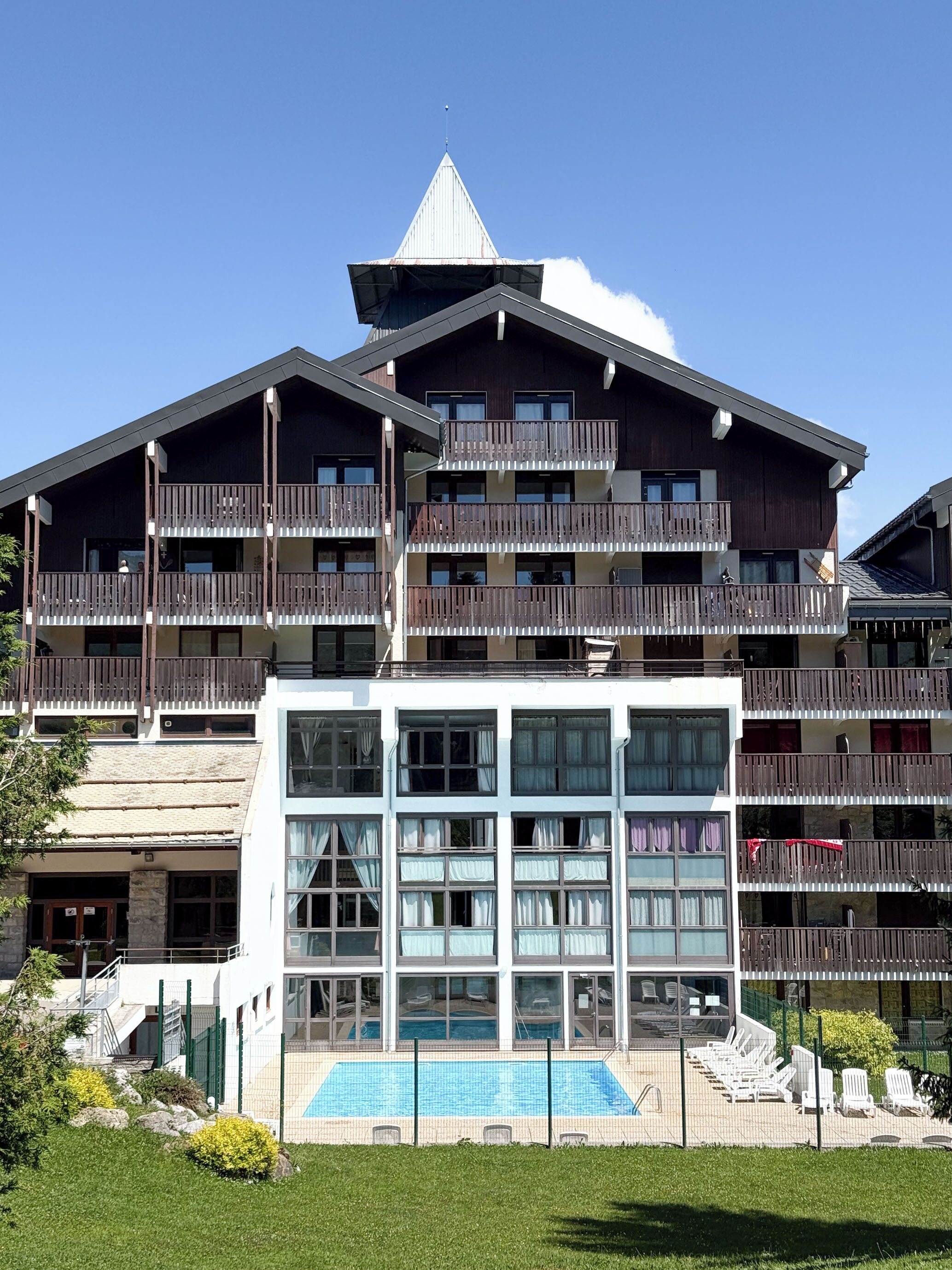 A multi-story hotel with a swimming pool and outdoor seating.