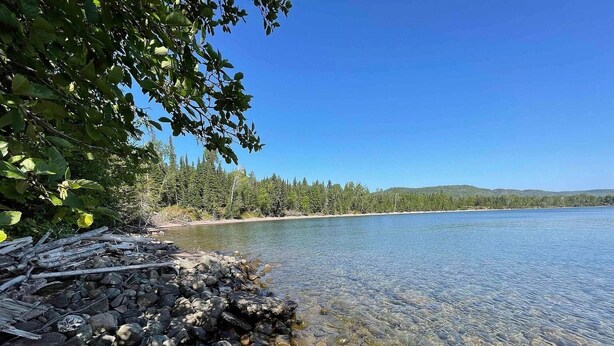 Un lago limpido con una riva rocciosa e una fitta foresta sullo sfondo.