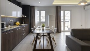 Een moderne keuken met een eetgedeelte, met een grote tafel, transparante stoelen en een ingebouwde oven.