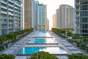 A modern high-rise building with a central swimming pool surrounded by lounge chairs and greenery. - ICON W BRICKELL ENDLESS OCEAN VIEW CORNER 2BR/2B #3208 (Miami)