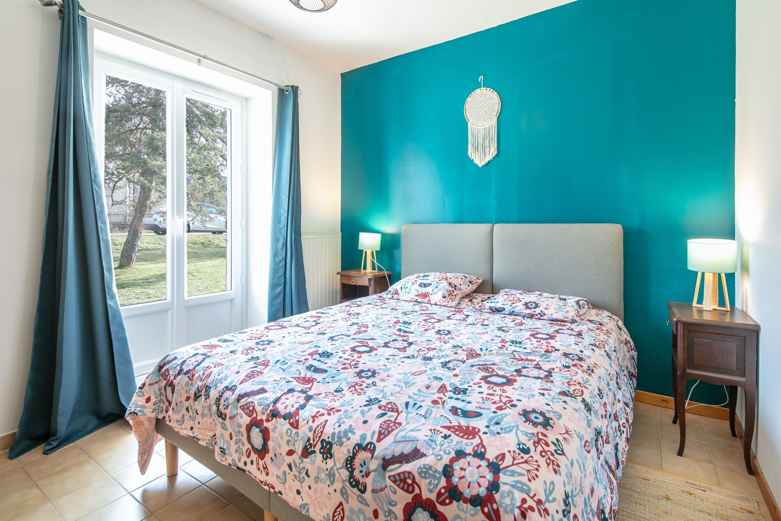 Una camera da letto con una parete verde acqua, una coperta a motivi e due lampade da comodino.