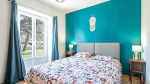 A bedroom with a teal accent wall, a patterned bedspread, and two bedside lamps.