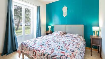 A bedroom with a teal accent wall, a patterned bedspread, and two bedside lamps.