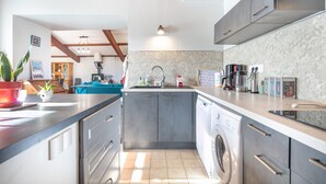 A modern kitchen with grey cabinets, a built-in washing machine, and a sink.
