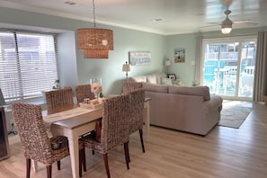 Un coin repas avec des chaises en osier, une table en bois et un ventilateur de plafond.