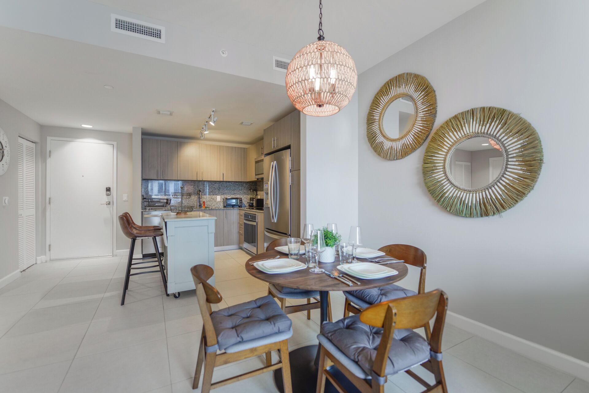 A modern kitchen with stainless steel appliances, a dining area with a round table, and two wall-mounted mirrors.