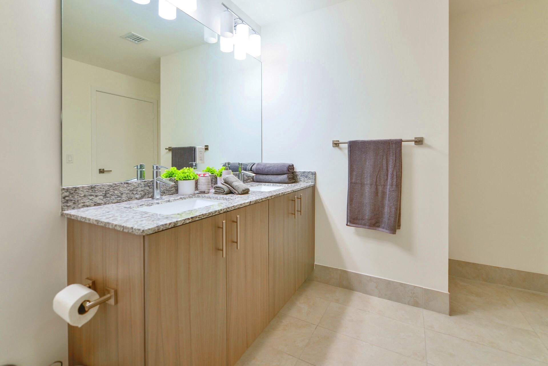 A bathroom with a marble countertop, a sink, a mirror, and a towel rack.