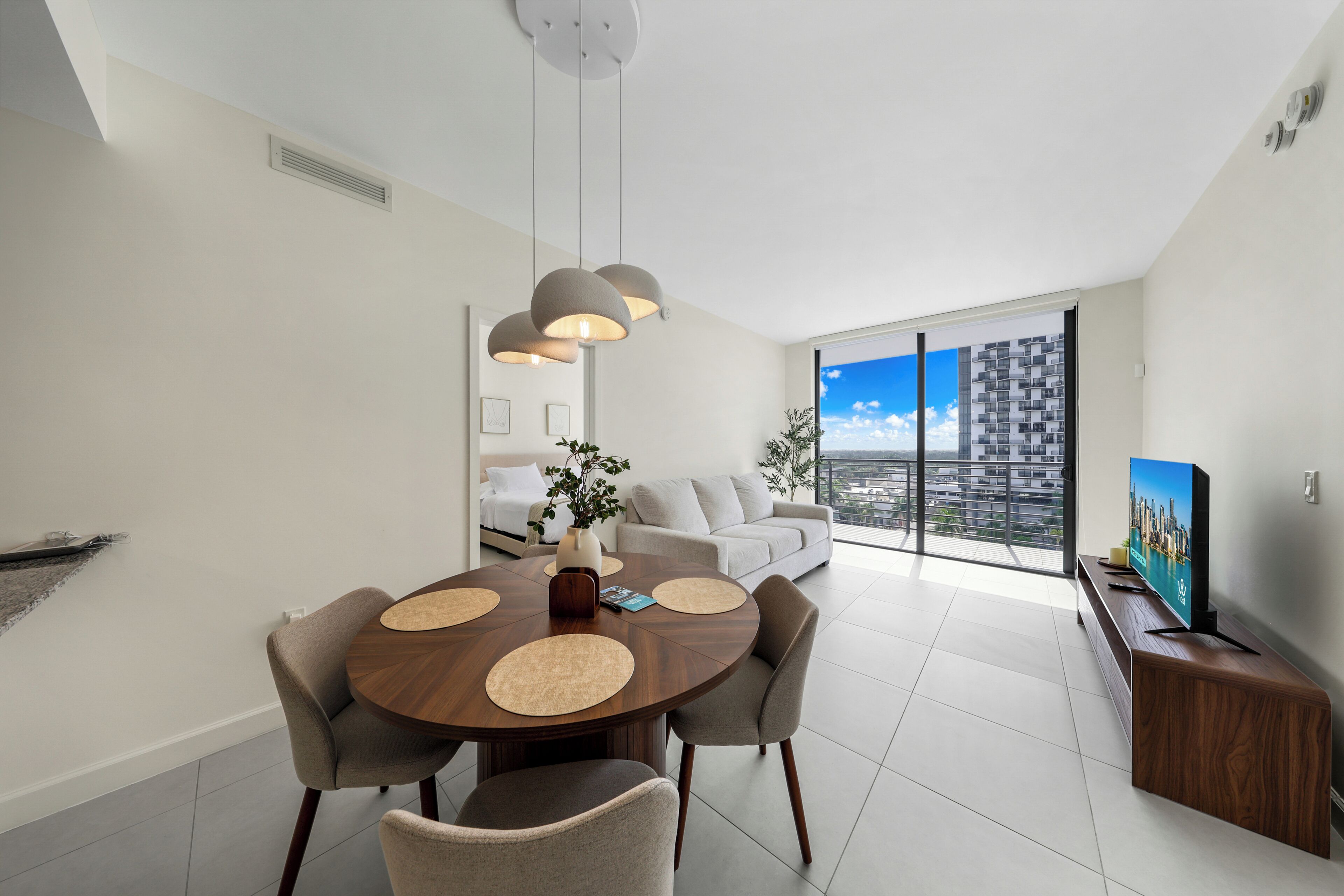 Una sala de estar moderna con comedor, un conjunto de sofás, una mesa de centro y un televisor sobre un mueble.