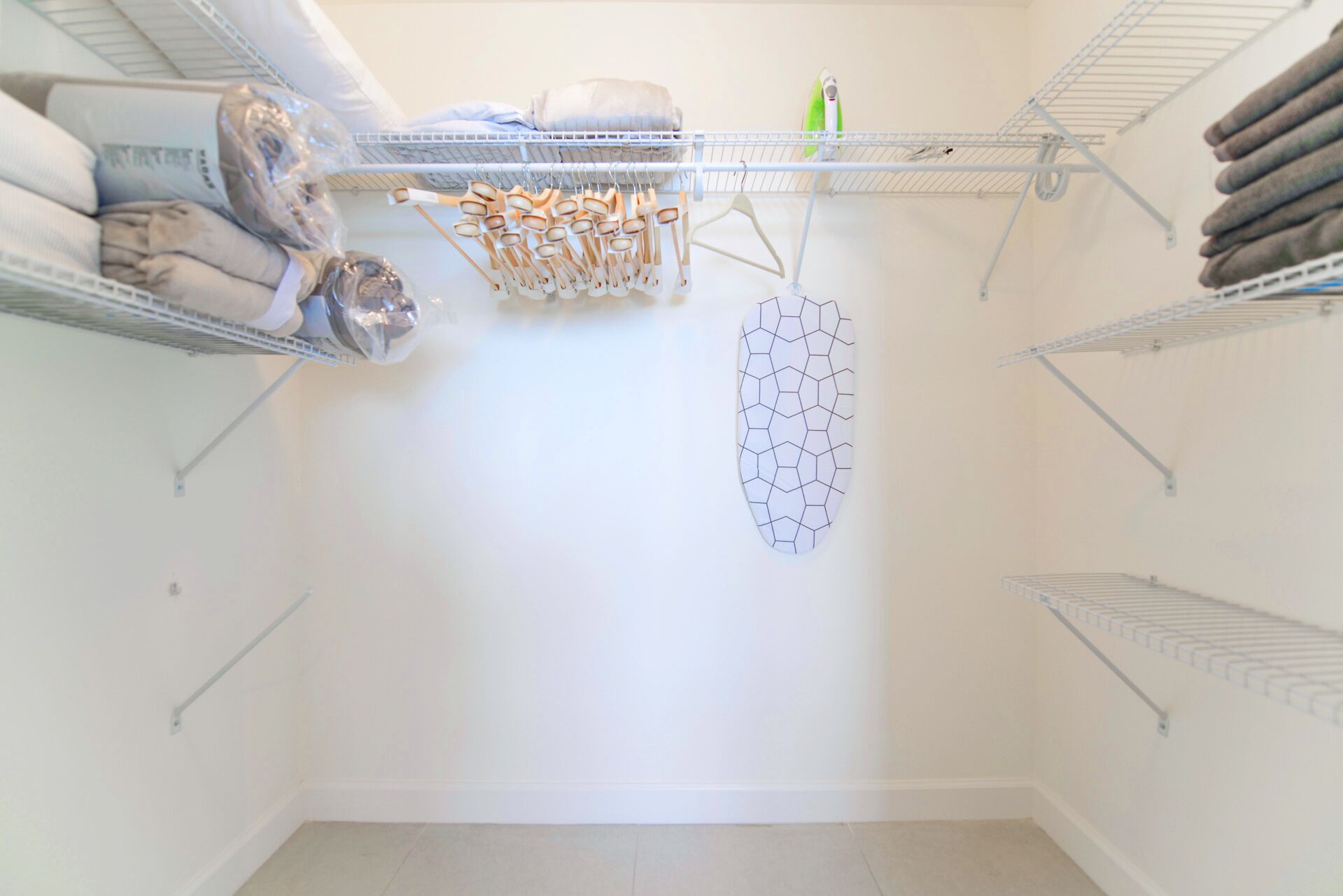 A storage closet with shelves for folded clothes, a drying rack, and a wall-mounted drying rack.