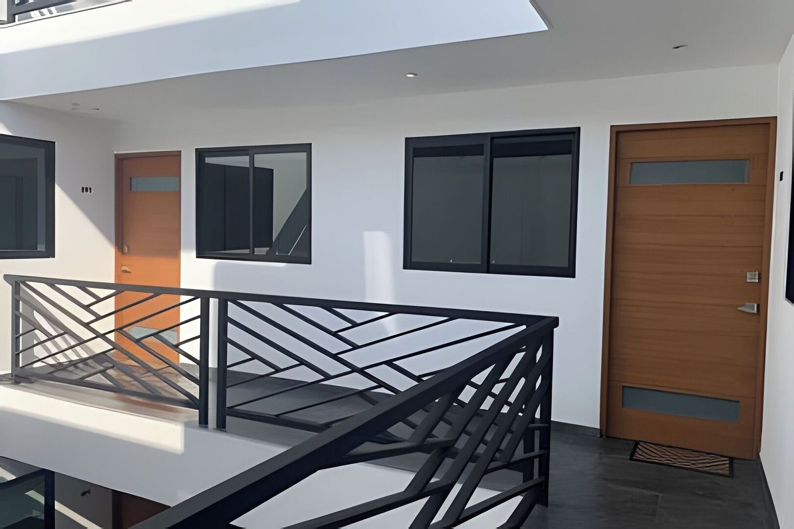 Un bâtiment moderne doté d’un balcon, de grandes fenêtres et d’une porte en bois.