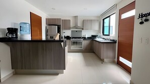Una cocina moderna con una isla central, horno empotrado y un amplio ventanal que proporciona luz natural.