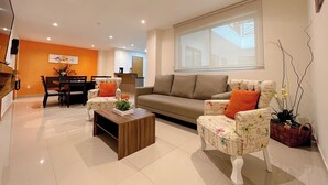 A modern living room with a sofa, two armchairs, a coffee table, and a dining area with chairs and a table.