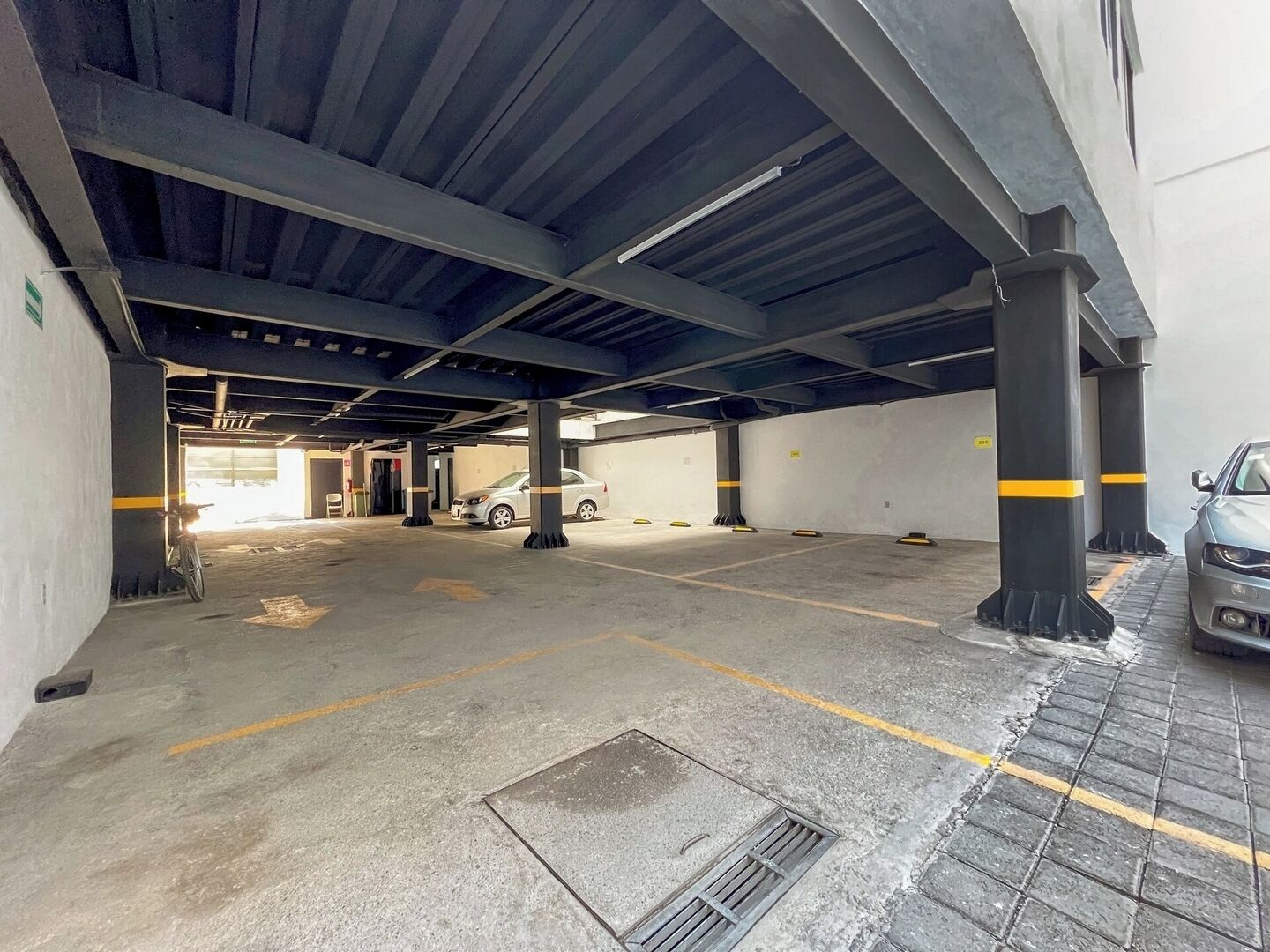 An underground parking garage with concrete floors, yellow lines, and metal pillars.