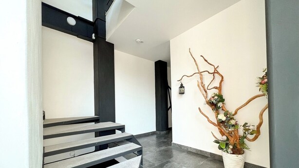 A modern staircase with a minimalist design, a wall-mounted decorative tree, and a small lantern.