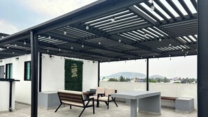 An outdoor patio with a pergola, seating area, and a view of the cityscape.