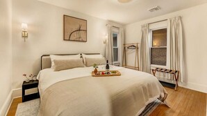 A neatly arranged bedroom with a bed, bedside table, lamp, and a tray with food and drink. - Elegant Historic 5BR Home in Downtown Stroudsburg (Stroudsburg)