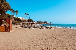 Una playa con tumbonas, sombrillas y una estructura de madera.
