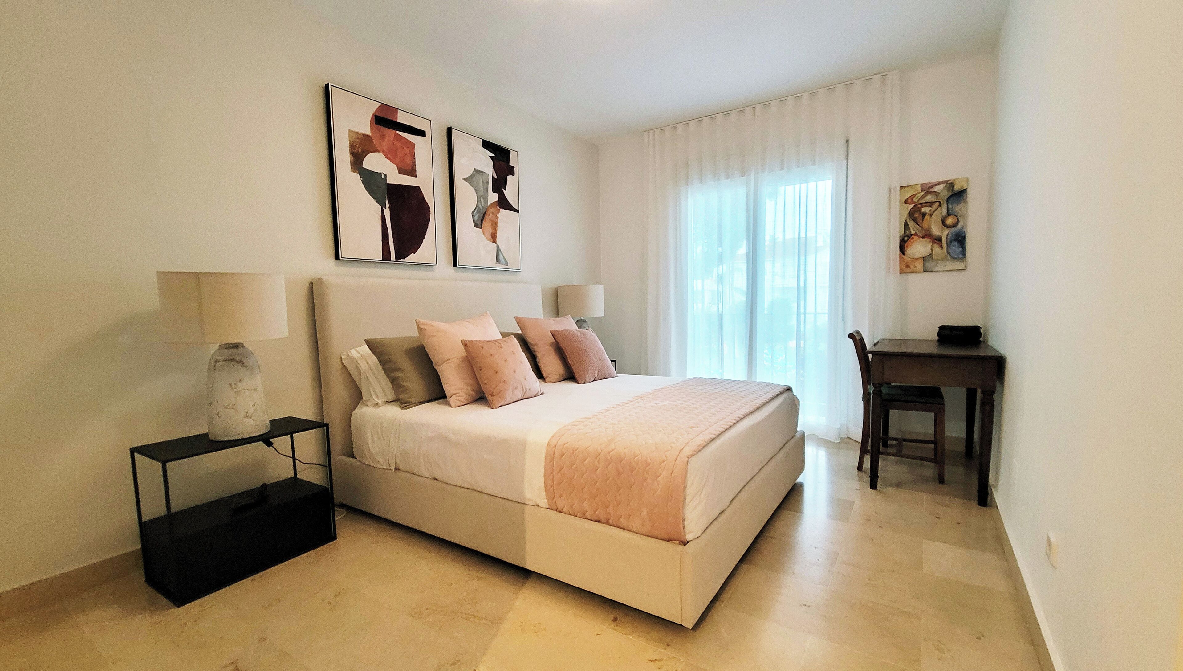 A bedroom with a bed, bedside tables, a desk, and chairs.
