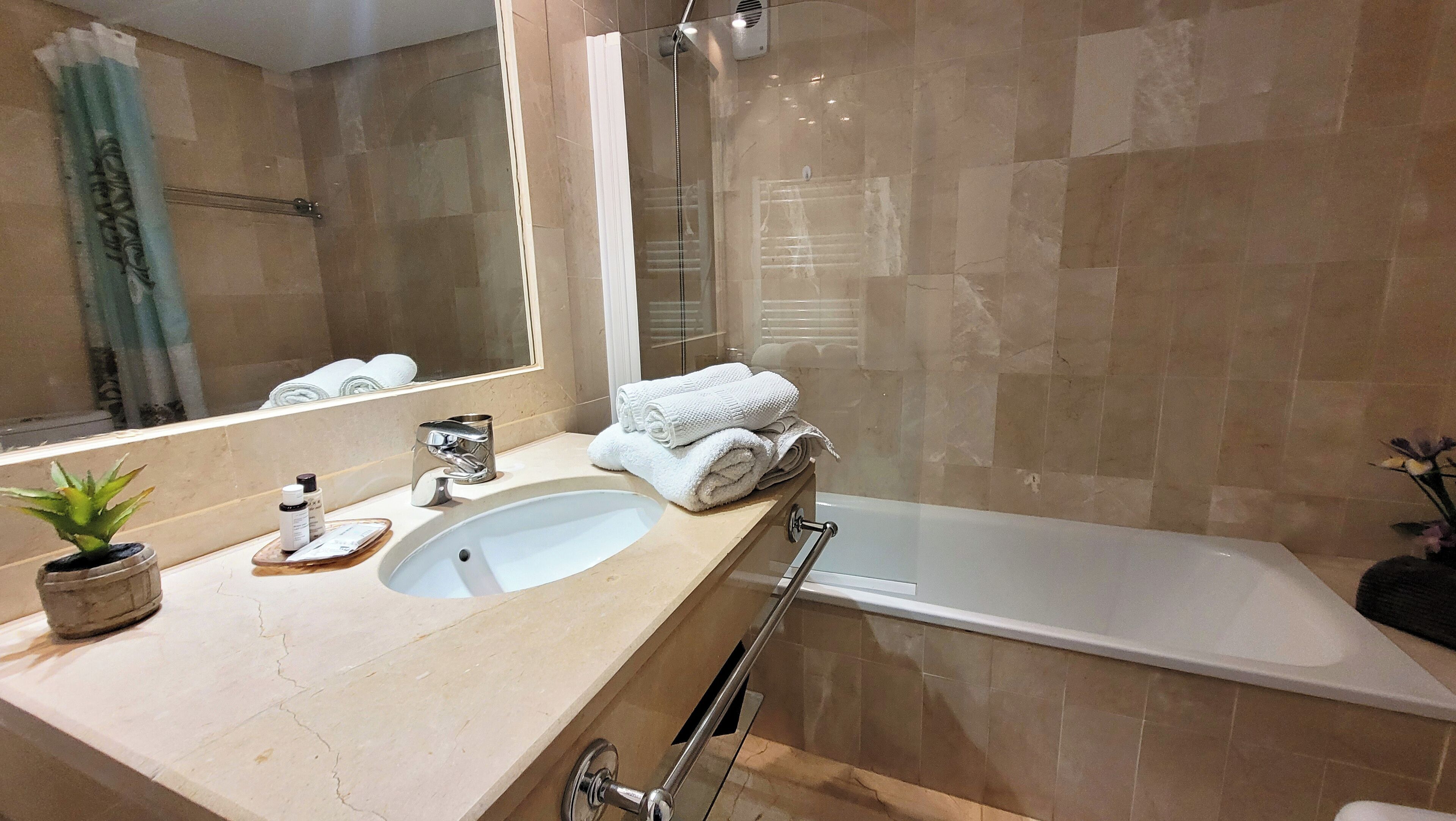 A bathroom with a sink, mirror, towel rack, and a bathtub.
