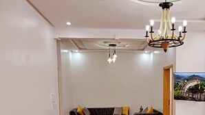 Una sala de estar con un sofá, una mesa de comedor con comida, una araña y un televisor en la pared.