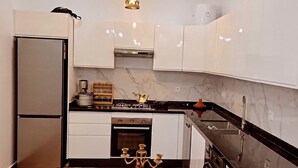 Una cocina moderna con armarios blancos, un refrigerador de acero inoxidable, una estufa a gas y una encimera de madera.