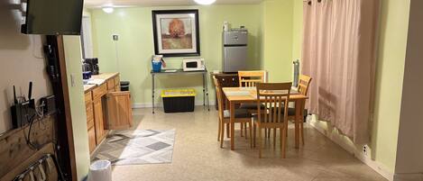 A compact kitchen with a dining area, a refrigerator, a microwave, and a coffee maker.