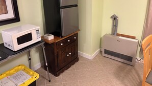Uma cozinha compacta com micro-ondas, frigorífico e ar condicionado.