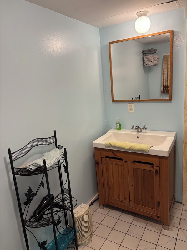 A bathroom with a white sink, wooden cabinets, a mirror, and a towel rack.