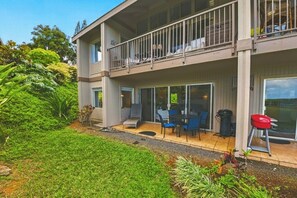 Ein zweistöckiges Gebäude mit einem Balkon, einer Terrasse mit Gartenmöbeln und einem Garten.
