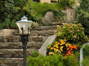 A stone staircase surrounded by lush greenery and vibrant flowers. - Zevnik Quiet Retreat with Stunning Views and Equestrian Activities - One Bedroom Apartment (Brežice)