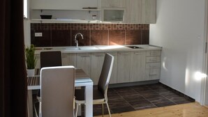 A modern kitchen with white cabinets, a dark backsplash, and a dining area with a table and chairs.