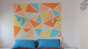 A bedroom with a geometric-patterned wall, a bed with blue pillows, and bedside tables. - Fashonable and Trendy Apartments Crikvenica - Studio Apartment with Balcony (Crikvenica)