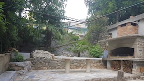 A stone patio with a rustic outdoor seating area, a stone wall, and a brick oven. - Fashonable and Trendy Apartments Crikvenica - Studio Apartment with Balcony (Crikvenica)