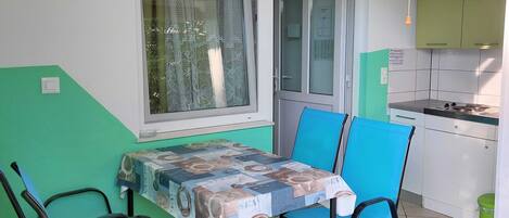 A small kitchen with a table and chairs, a window with lace curtains, and a green and white color scheme.