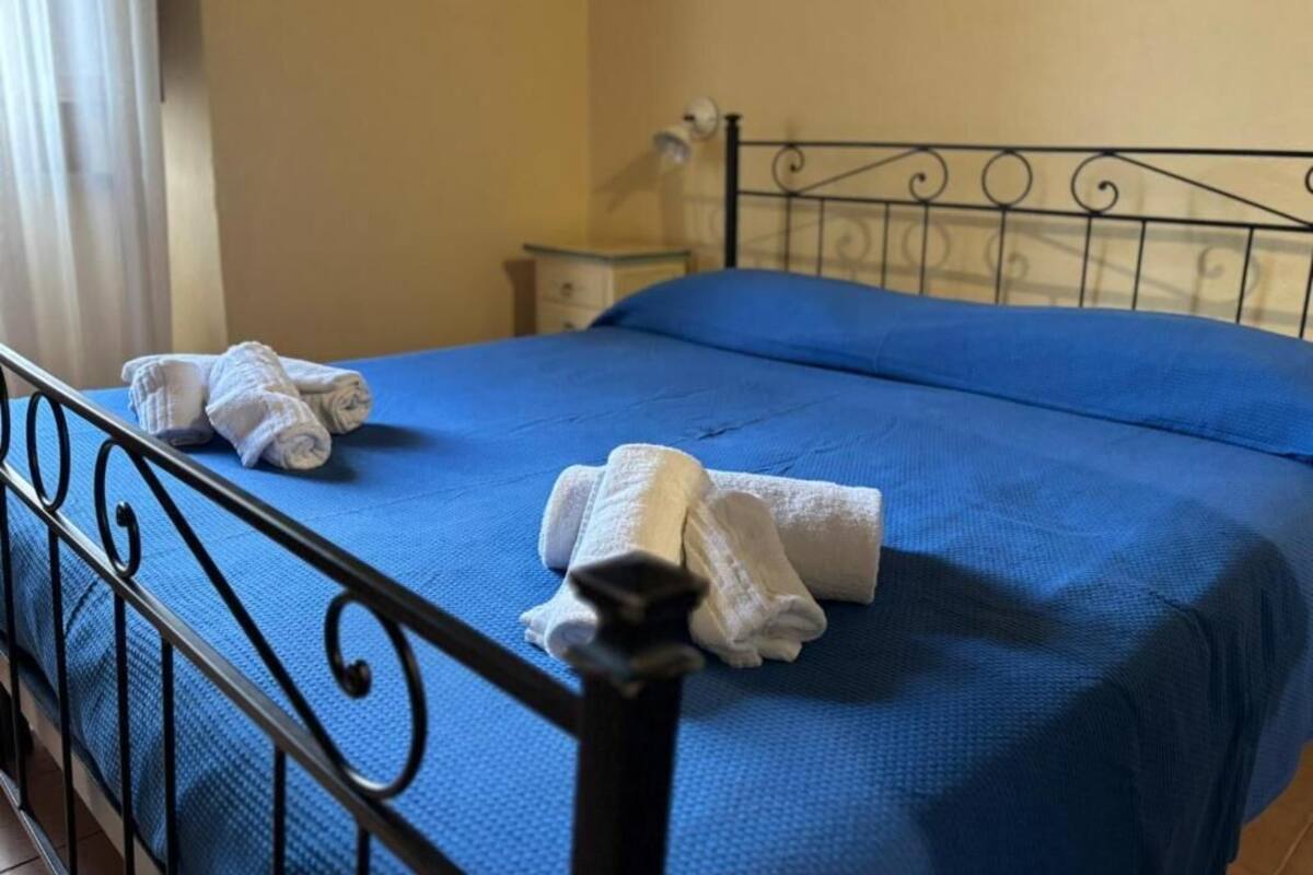 A bed with a blue bedspread and white towels.