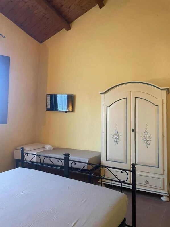 Un dormitorio con cama, armario y televisor en la pared.