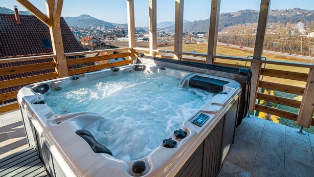 Uma banheira de hidromassagem com deck de madeira e vista para uma cidade e montanhas.